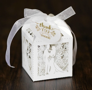 Detail of white laser-cut hollow wedding candy box with gold Thank You tag and ribbon