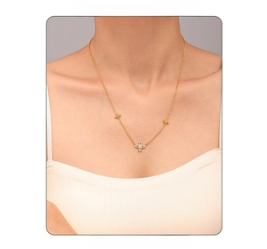 Detail of model wearing a gold clover necklace with sparkling white zircon flower pendants