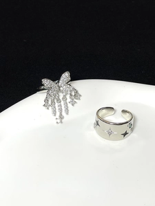 Detail of silver butterfly tassel ring and wide starburst band with zircon stones