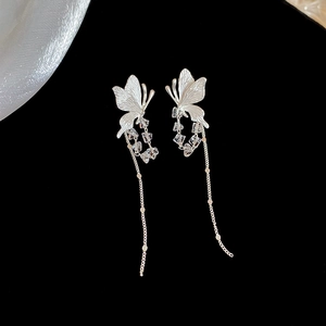 Close-up of silver butterfly tassel earrings with crystal beads on a black background