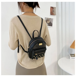 Close-up of black leather mini backpack with golden studs and metal brand plaque