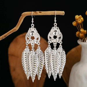 Macro detail of silver leaf drop earrings hanging on a natural wooden branch