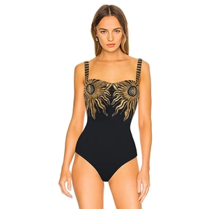 Detail of black one-piece swimsuit featuring elegant golden sunburst embroidery on the chest