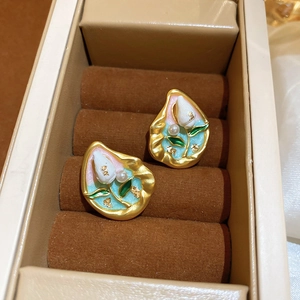 Detailed macro view of vintage pearl flower stud earrings with gold plating and enamel inlay