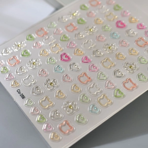 Macro shot of 3D embossed nail stickers featuring pastel bears and floral patterns with rhinestones