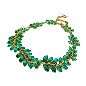 Vintage style gold necklace with green oval gemstone and leaf pattern on white background