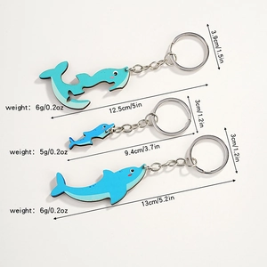 Three cute wooden dolphin keychains in various sizes with metal rings for bags