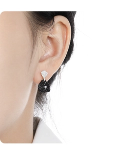 Detail showing irregular black textured earring with zircon inlay and silver hammered metal