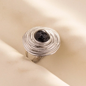 Macro detail of concentric spiral silver ring with a black marble textured gemstone