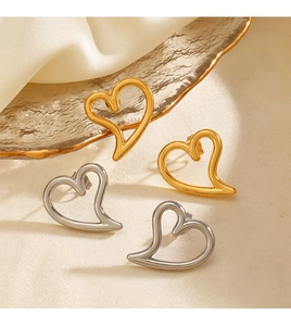 Detailed close-up of gold and silver heart-shaped stud earrings on a silk background