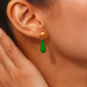 Detailed view of model wearing asymmetric gold-plated lava teardrop earrings with green enamel