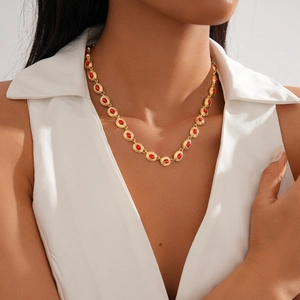 Vintage gold necklace with oval red rhinestones worn by a model in a white V-neck top