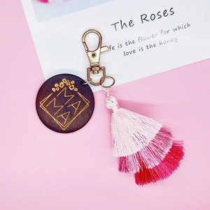Close-up of MAMA wooden keychain with pink gradient fringe and leopard print patterns