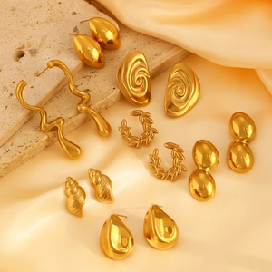 Collection of golden geometric earrings featuring teardrop and spiral designs on silk