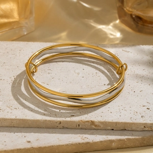 Minimalist geometric mixed gold and silver layered bangle bracelets on a stone base