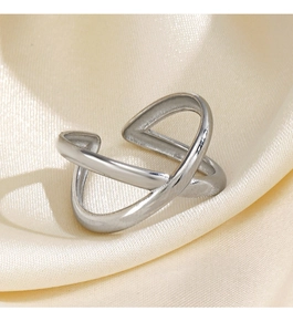 Macro shot of a silver criss-cross open ring on a textured beige satin surface