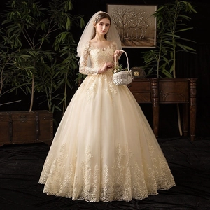 Elegante abito da sposa color champagne con maniche lunghe in pizzo e ricami floreali