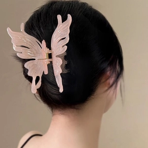 Détail d'une grande pince à cheveux papillon rose translucide sur cheveux longs noirs