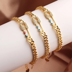 Tres pulseras doradas con alfileres de pedrería y amuletos de ojo turco de colores