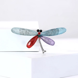 Detailed view of dragonfly brooch with multicolored wings and inlaid crystal stones