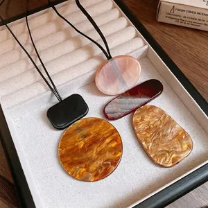 Assorted geometric resin pendants with marble textures on a minimalist display