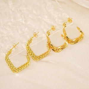 Macro shot of gold multi-layered square twisted earrings on rippled texture background