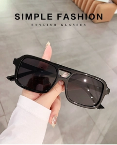 Close-up of stylish black square frame sunglasses held by hand with clean minimal text