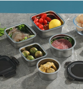 Five assorted stainless steel food containers with black lids on a marble surface
