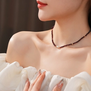 Detailed shot of garnet bead necklace with a freshwater pearl on a model's neck