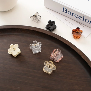 Mini floral acrylic hair clips in various colors scattered on a wooden tray
