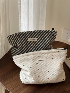 Close-up of woven polka dot cosmetic bags with simple wish label on a wooden table