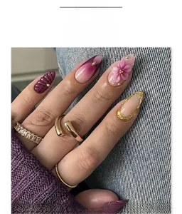 Detalle de flores 3D y uñas postizas degradadas en violeta con adornos dorados