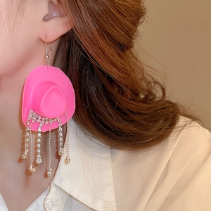 Detailed side view of pink cowboy hat earrings with sparkling rhinestone tassels on a model