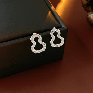 Macro shot of silver gourd-shaped earrings with faceted texture on a black jewelry box