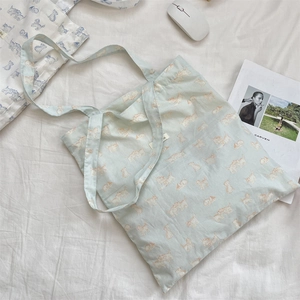 Detail of light blue canvas tote bag with cute brown cat prints on textured fabric