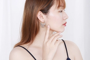 Detail view of silver hollow flower-shaped stainless steel hoop earrings on model