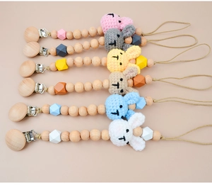 Detailed flat lay of six colorful crocheted bunny pacifier clips with wooden beads