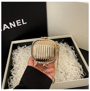 Detail of a mini gold hardshell evening clutch with vertical ribbed texture and metal chain