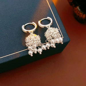 Detail of silver hoop earrings with hollow bell charm and hanging pearl tassels