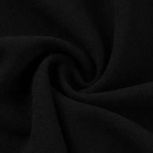 Gros plan du tissu texturé noir montrant le grain délicat et le drapé fluide de la robe