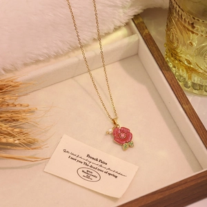 Détail du pendentif rose vintage avec pétales en émail rose et perle sur chaîne dorée