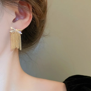 Close-up of elegant gold tassel earrings with zircon studs worn by a female model