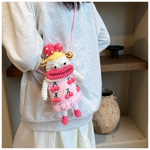 Detailed close-up of a pink handmade crochet crossbody bag with a cute cartoon face