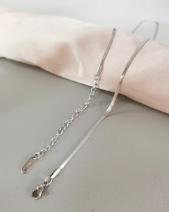 Polished stainless steel snake chain necklace with lobster clasp on pink silk