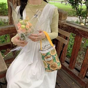Detailed shot of sunflower canvas bucket bag with yellow straps and wave trim accents