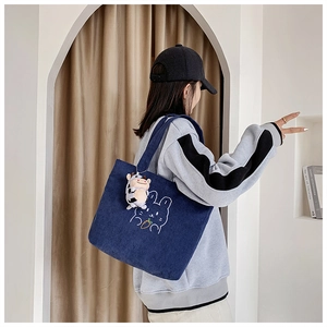 Detail of dark blue corduroy tote bag with rabbit embroidery and cow plush charm