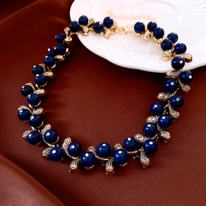 Detail of vintage resin bead necklace with gold textured leaves on silk background
