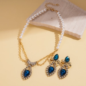 Detail of luxury vintage necklace with pearls, diamond bow, and blue water drop gemstone