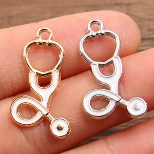 Detail showing gold and silver stethoscope charms with white enamel for DIY jewelry