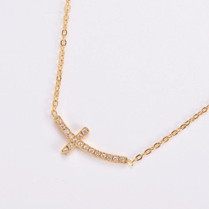 Macro shot of gold-plated horizontal cross necklace with sparkling zircon crystals